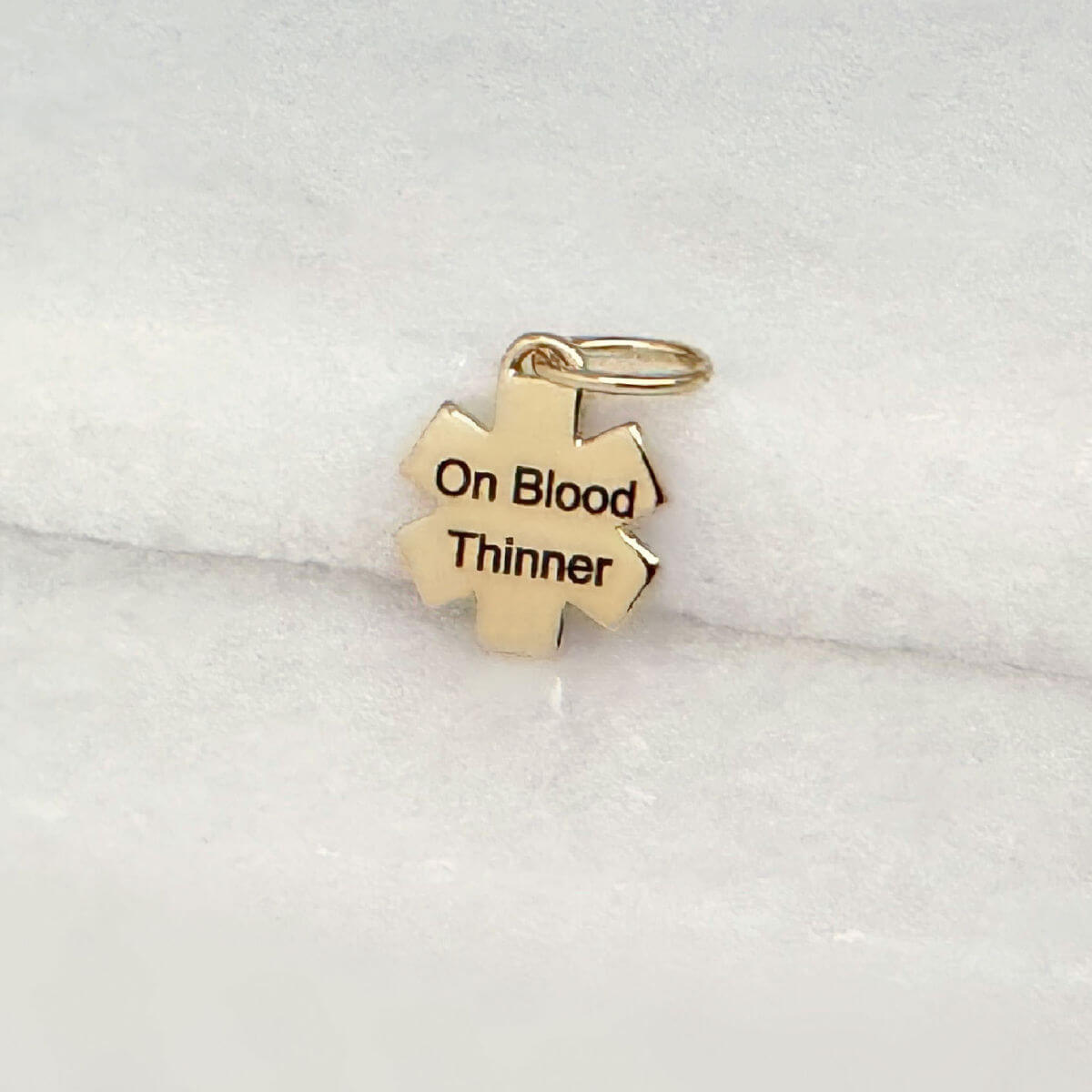 Gold medical ID star of life charm with blood thinner engraving shown on the back side