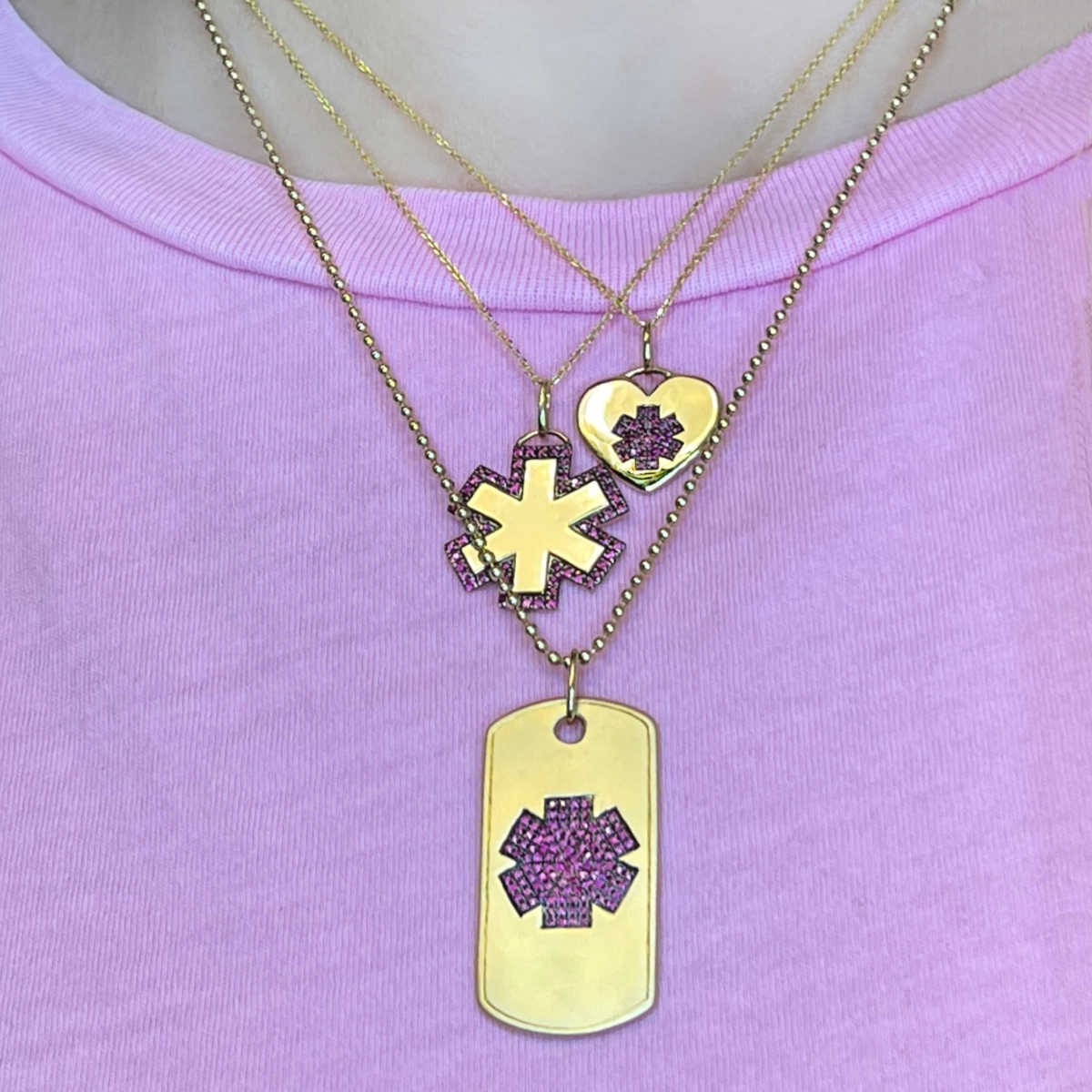 Woman wearing 14k gold and ruby medical ID necklaces, heart, star of life, and dog tag engraved medical alert charms