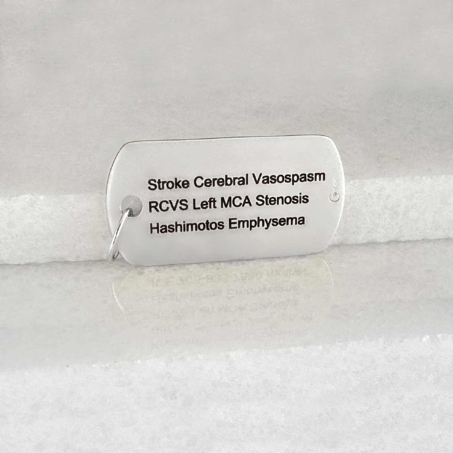 White gold medical ID dog tag with personalized engraving shown on the back side