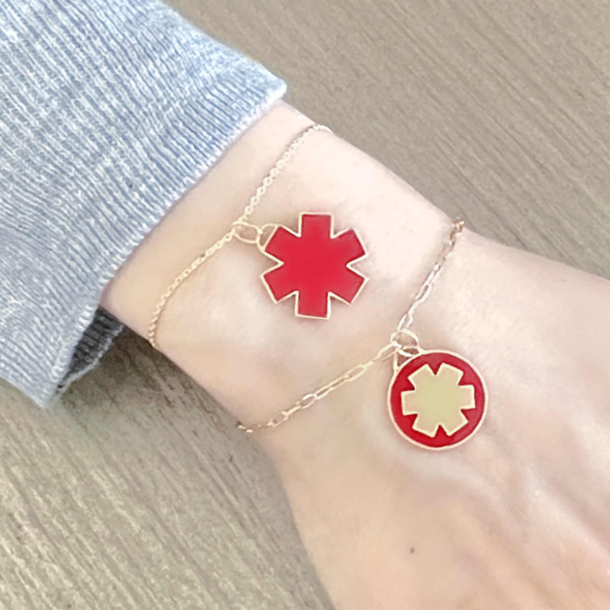 Woman Wearing 2 Medical ID Charm Bracelets. Engraved 14k Gold Medical Alert Jewelry with Red Enamel Star of Life