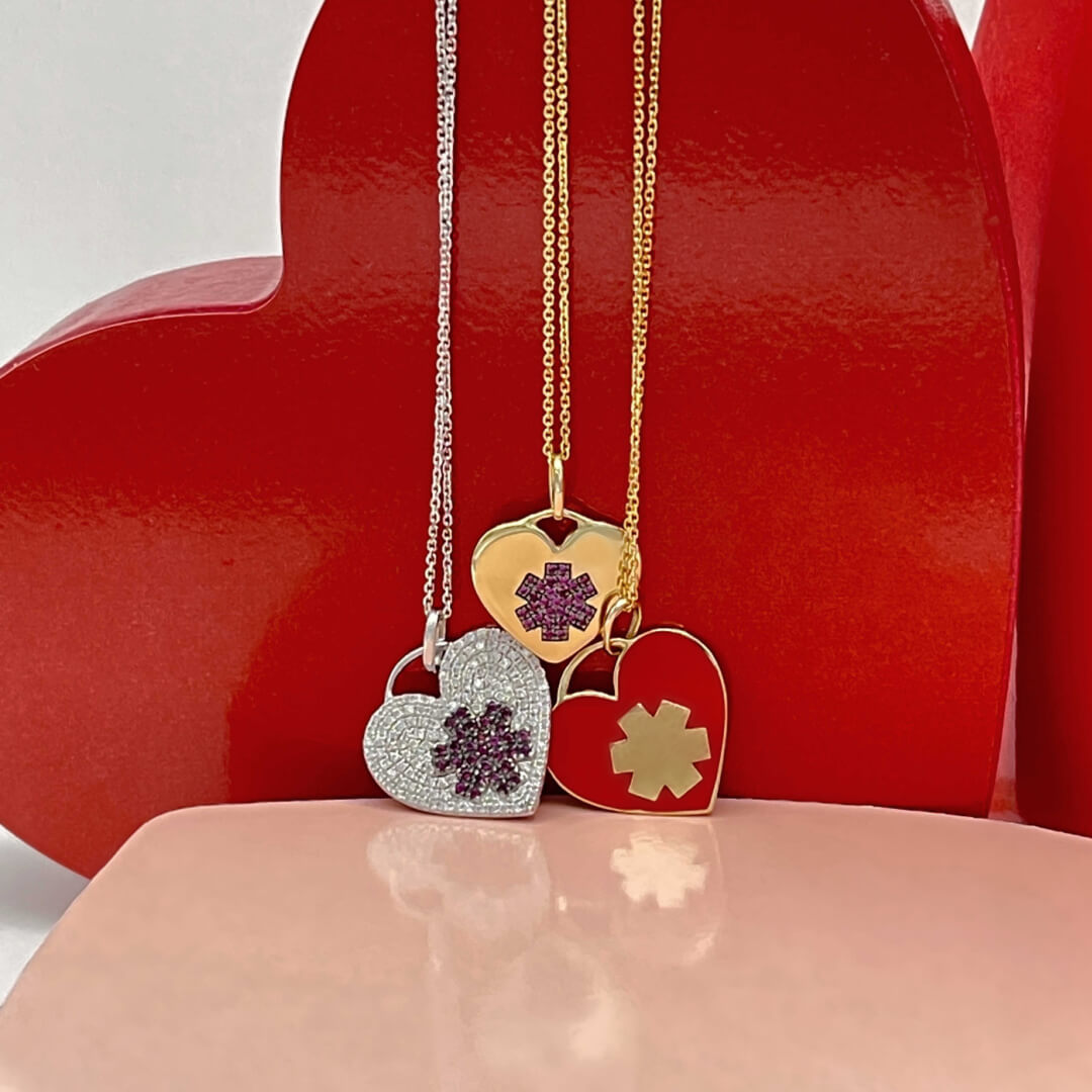 Gold heart medical ID charms with diamonds, enamel, & rubies, styled on necklace and bracelet chains