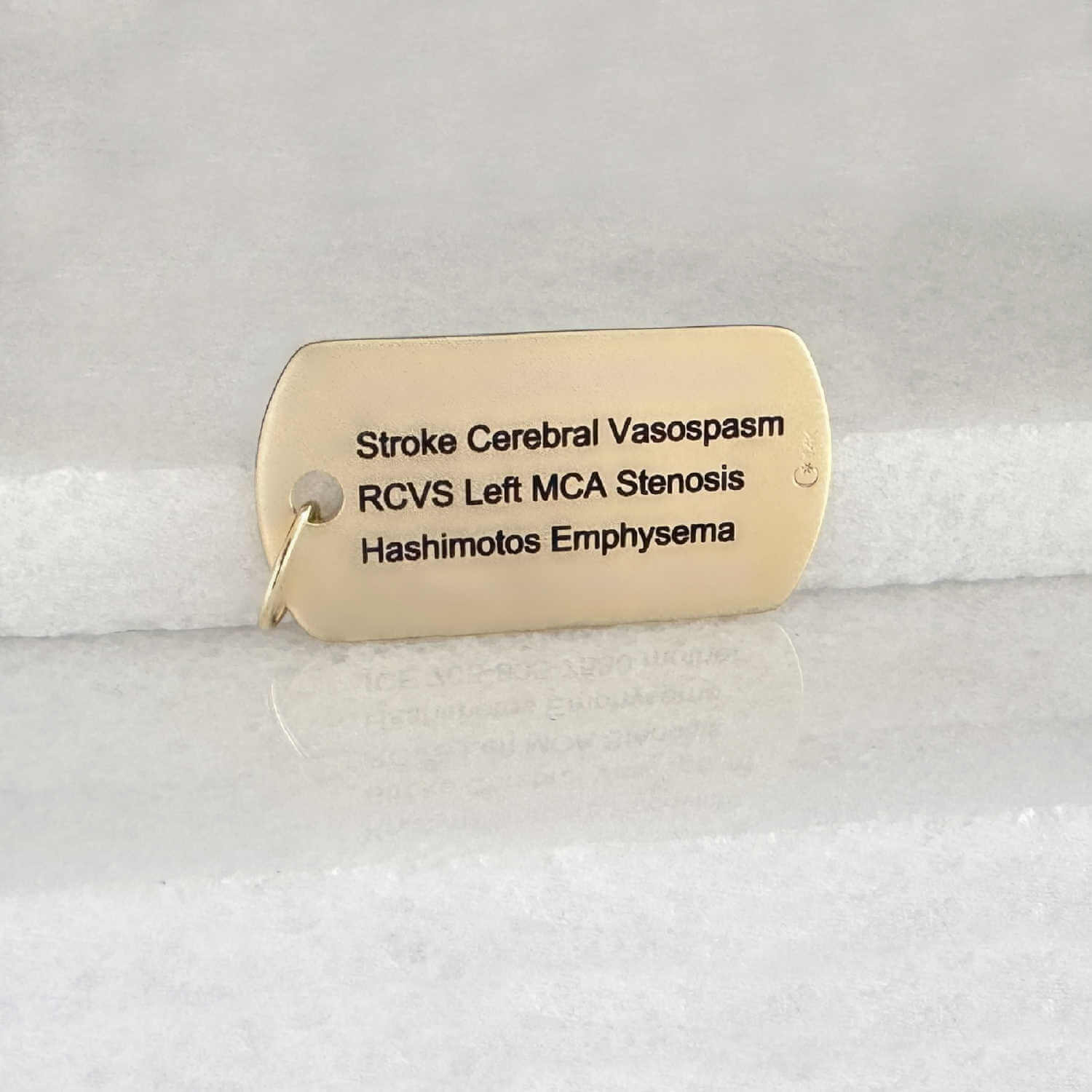 Gold medical ID dog tag with personalized engraving shown on the back side