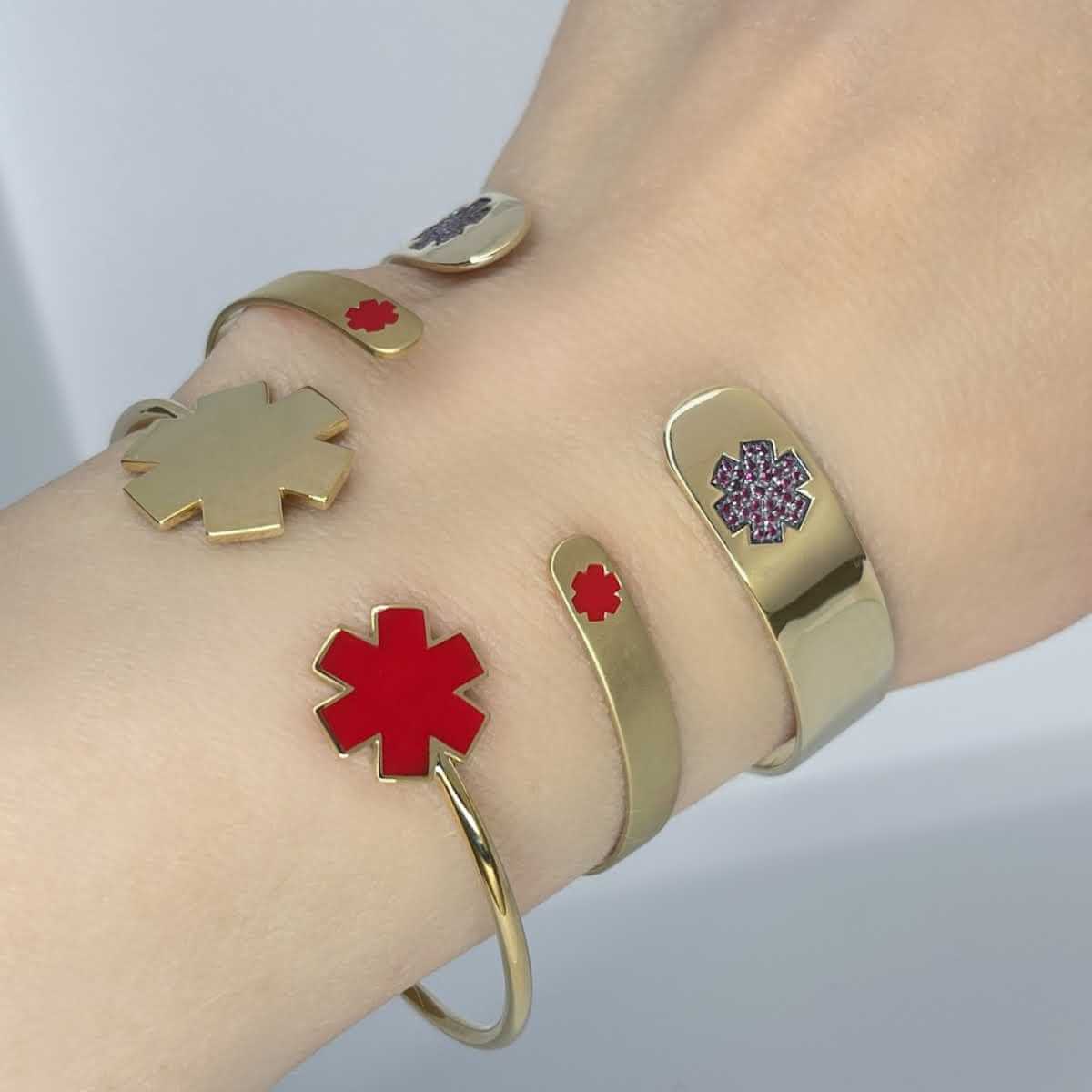 Woman wearing medical ID cuff bracelets in 14k gold. Custom engraved star of life medical alert
